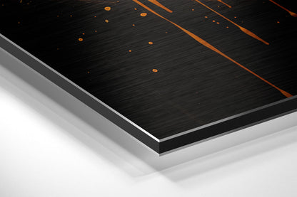 Close-up angled view of layered Dibond wall art showing black brushed surface with orange geometric lines and white backing layers.