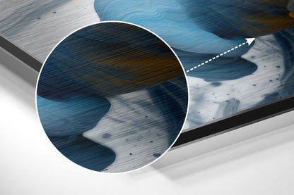 Close-up detail of brushed aluminum wall art showing layered blue and white tones with arrow pointer and textured surface.