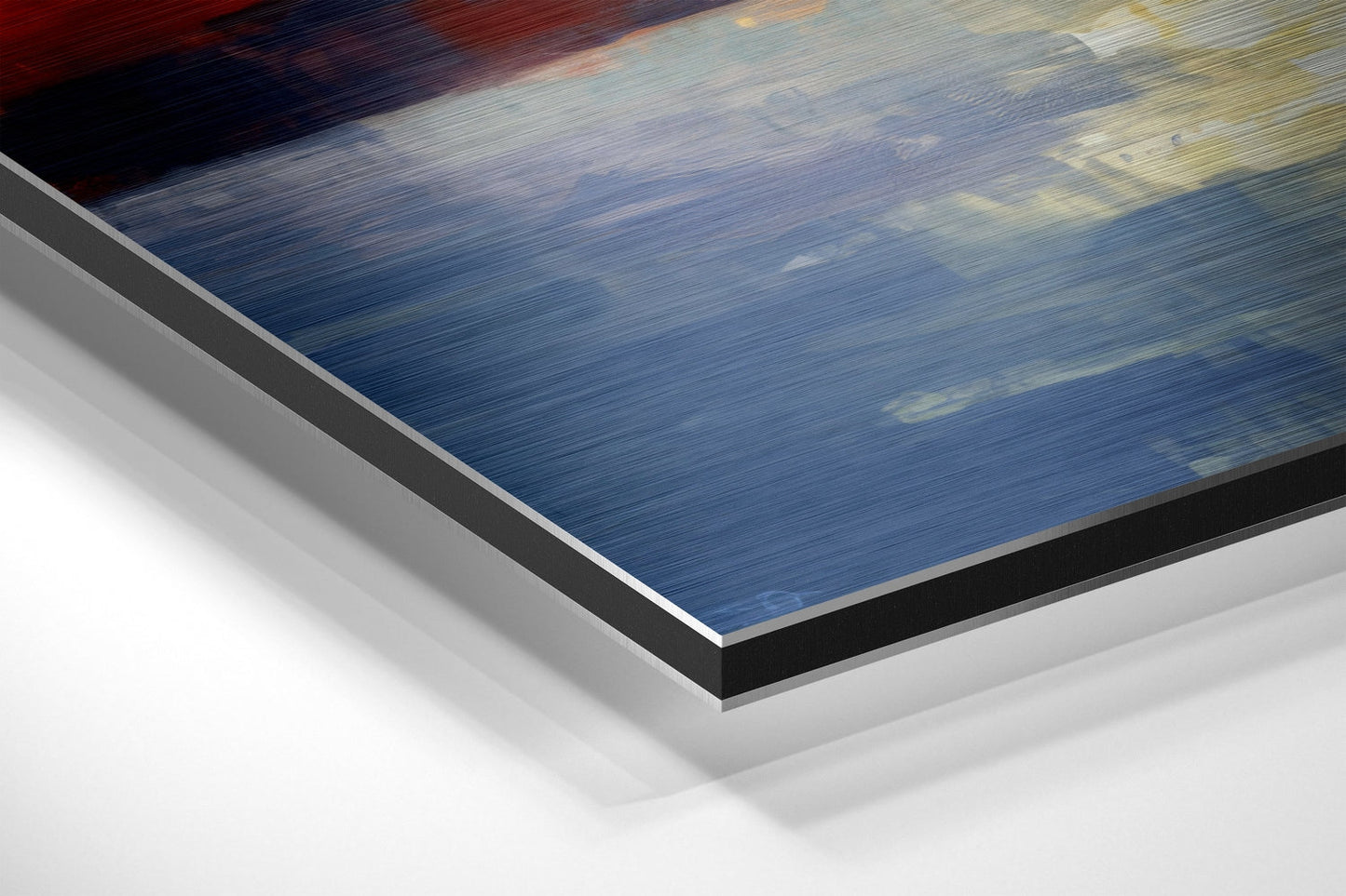 Close-up angled view of brushed aluminum Dibond print edges showing blue water scene with white and black mounting layers.