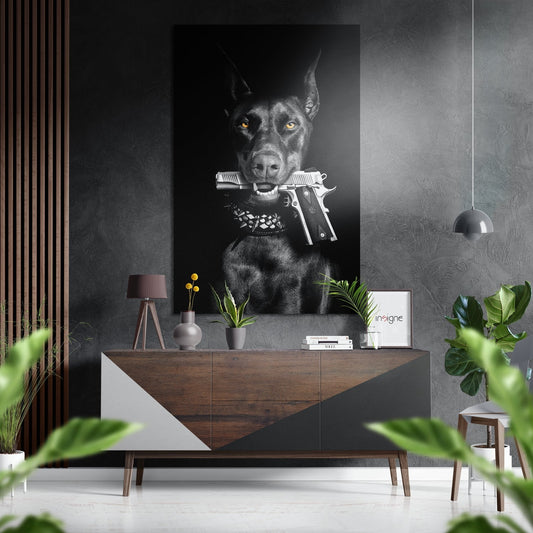 Black Doberman holding silver pistols in mouth against dark background, displayed above wooden dresser in modern interior setting.