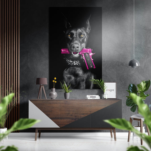 Black Doberman with pink pistol artwork displayed above wooden console table in modern interior setting with plants and pendant light.