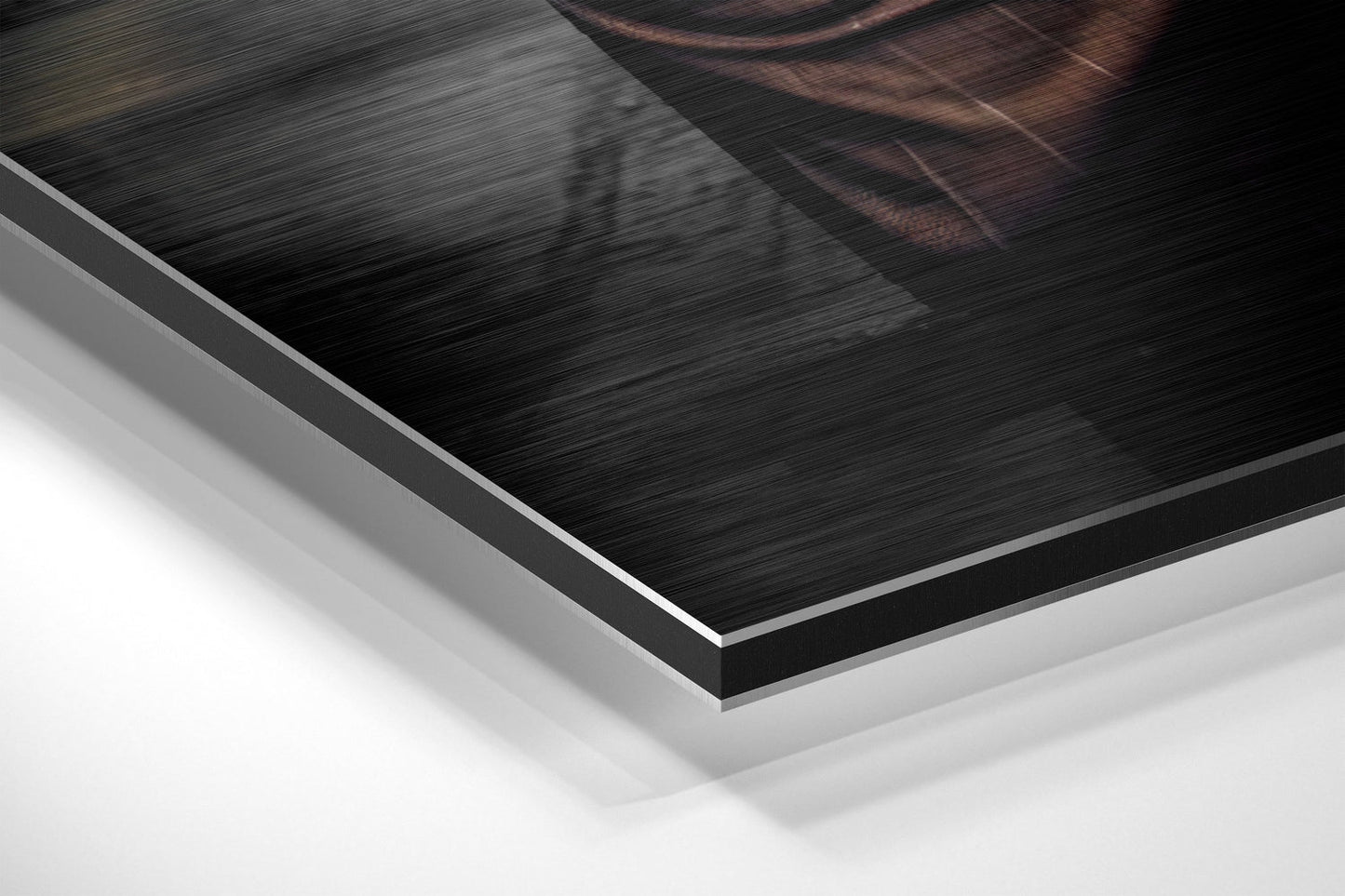 Close-up angled view of brushed aluminum Dibond print layers showing black brushed metal surface with white backing material.