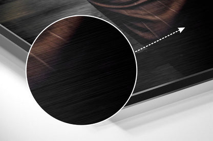 Close-up angled view of circular brushed aluminum wall art with white border and directional arrow on dark textured background.