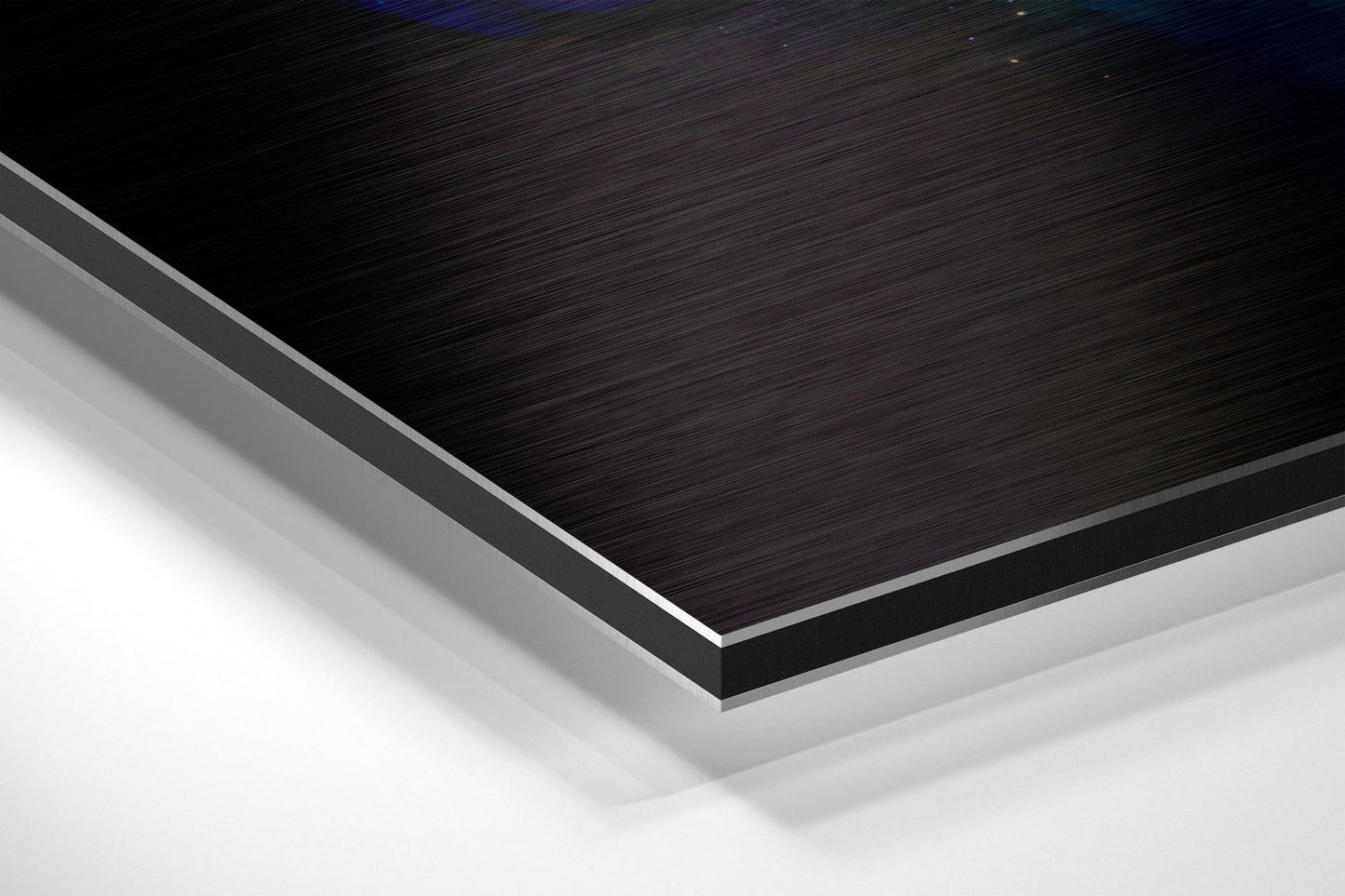 Close-up angled view of layered Dibond panel showing black brushed aluminum top surface with gray and white composite layers beneath.