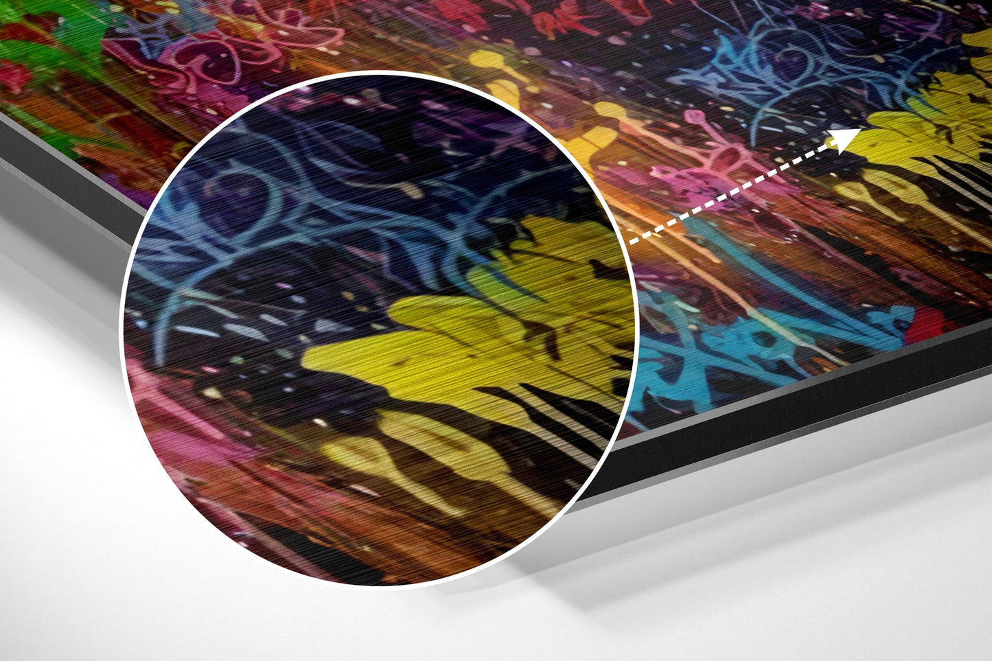 Close-up detail of colorful graffiti art on brushed aluminum showing yellow, blue, pink, and orange spray paint strokes with dimensional perspective view.