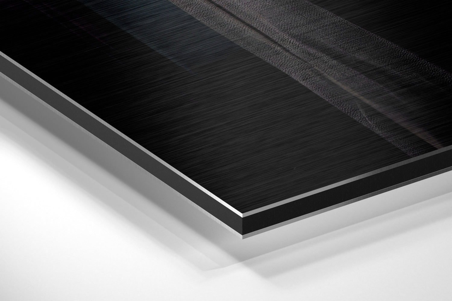 Angled close-up of layered Dibond materials showing brushed black aluminum surface with white backing and gray edge detail.