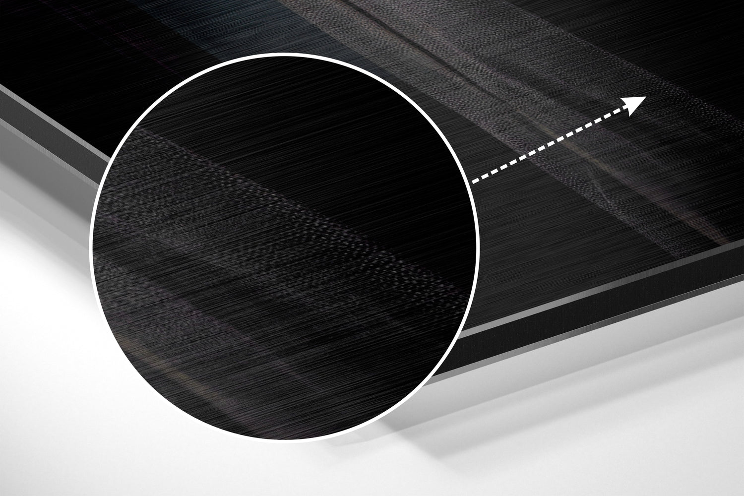 Close-up angled view of brushed aluminum Dibond wall art showing circular black textured center with white border and directional arrow detail.