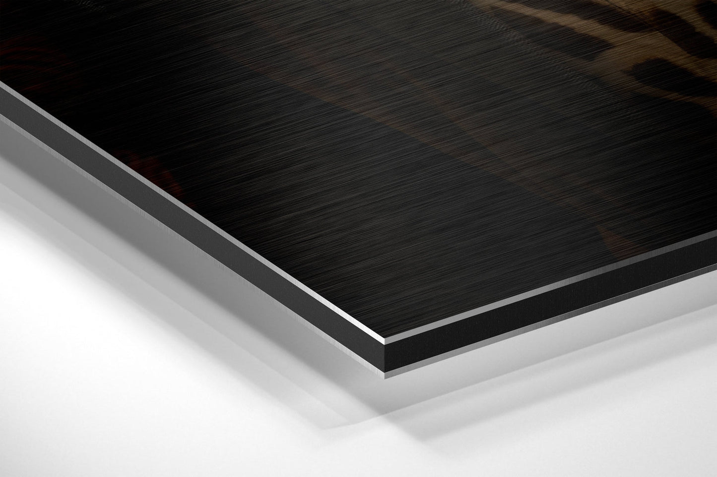 Close-up angled view of layered Dibond panel showing brushed black surface with white aluminum core and backing visible at edge.