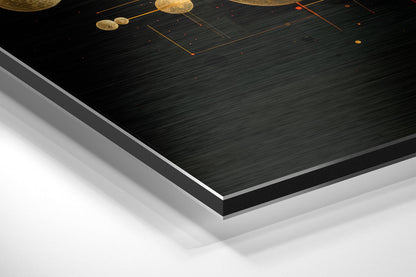 Angled view of layered Dibond wall art showing black brushed aluminum surface with gold spheres and orange geometric lines, displaying edge construction and white backing.