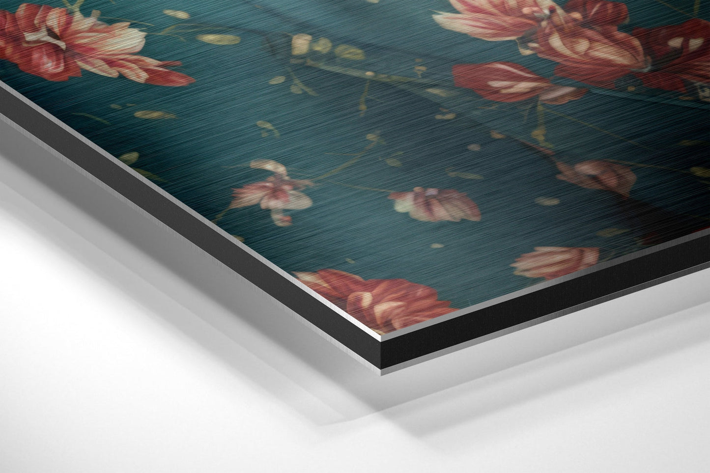 Close-up angled view of layered brushed aluminum and black edge framing a teal floral print with red roses.