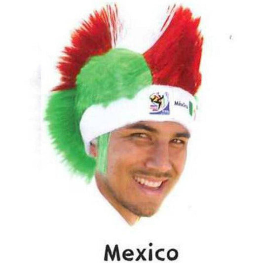 Man wearing green and red mohawk wig with white headband labeled Mexico, smiling at camera.