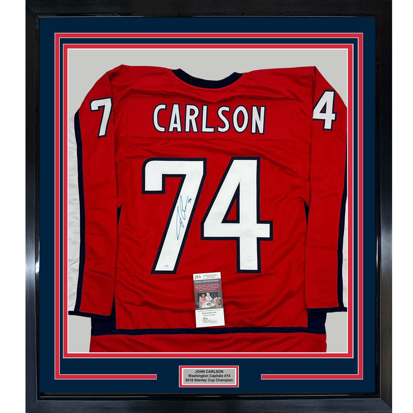 Red Washington Capitals hockey jersey number 74 signed by John Carlson, framed with blue and red matting and JSA authentication certificate visible.