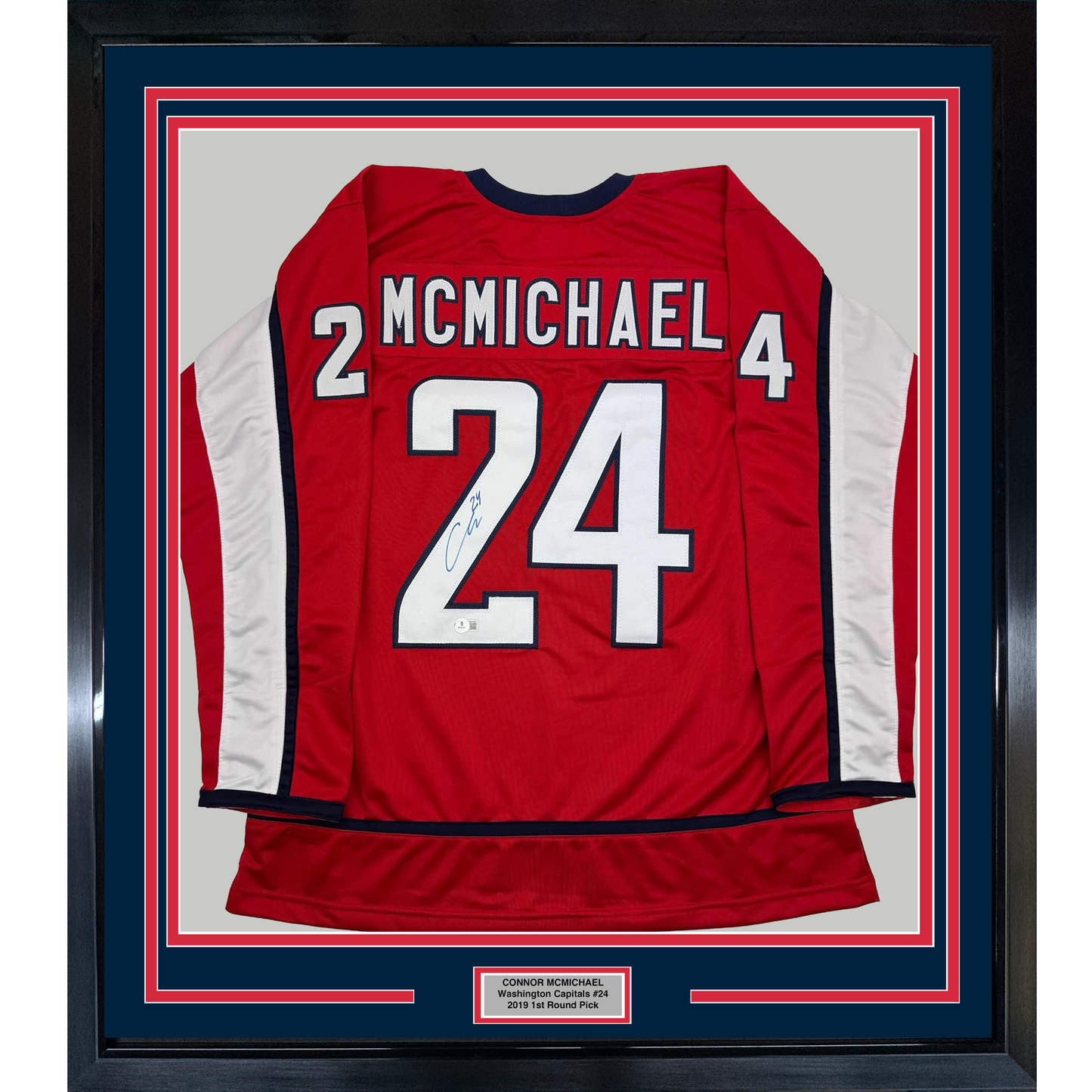 Red Washington Capitals hockey jersey number 24 with McMichael name, signed, framed with blue and red borders and nameplate.