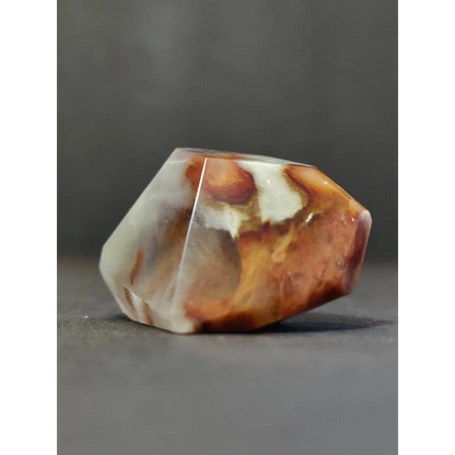 A polished freeform amphibole angel phantom quartz stone with faceted amber and cream swirls in quartz polished freeform style