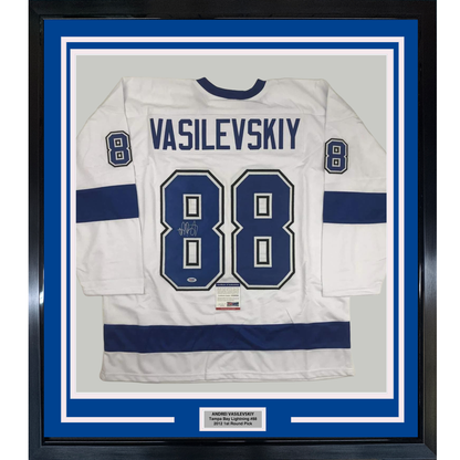 Framed white Tampa Bay Lightning hockey jersey number 88 with "VASILEVSKIY" name plate and autograph, displayed against blue matting in black frame.