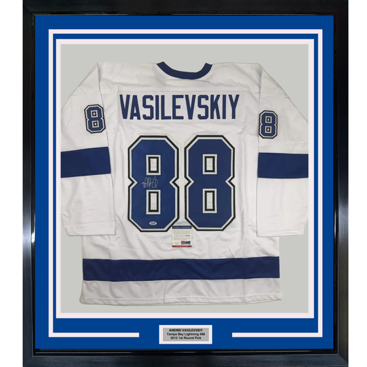 Framed white Tampa Bay Lightning hockey jersey number 88 with "VASILEVSKIY" name plate and autograph, displayed against blue matting in black frame.