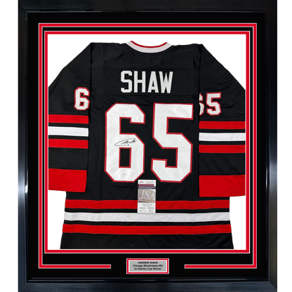 Framed black Chicago Blackhawks jersey number 65 with "SHAW" nameplate, red and white horizontal stripes, signed and authenticated with JSA certificate.