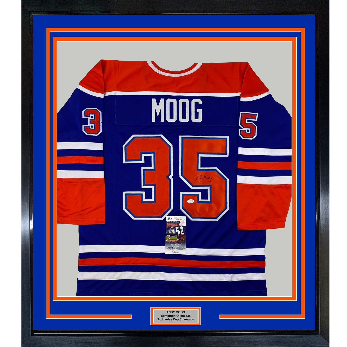 Framed Edmonton Oilers hockey jersey number 35 with "MOOG" nameplate, navy blue and red striped design, displayed front-facing against blue matting with orange border.