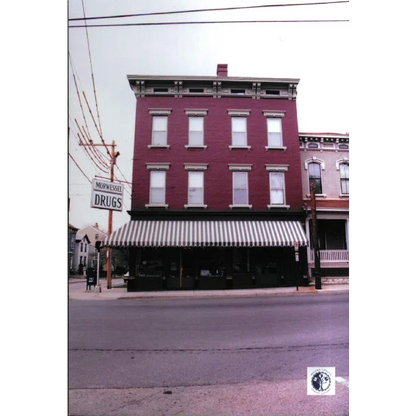A red brick building with white-trimmed windows and a black-and-white striped awning for vintage cocillana morphine pharmacy label Morwessel Drugs