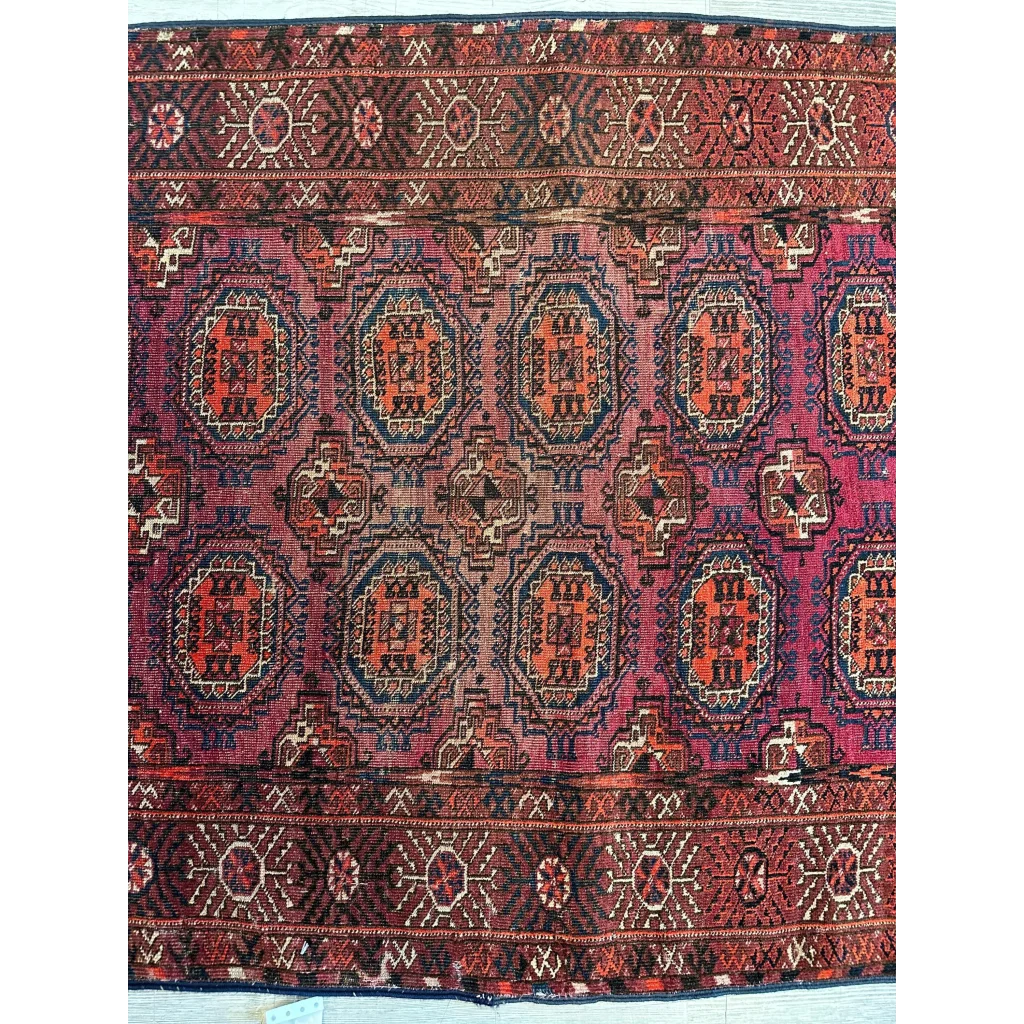 Antique 1910s Turkoman rug with dense geometric patterns in deep red, dark blue and ivory wool pile