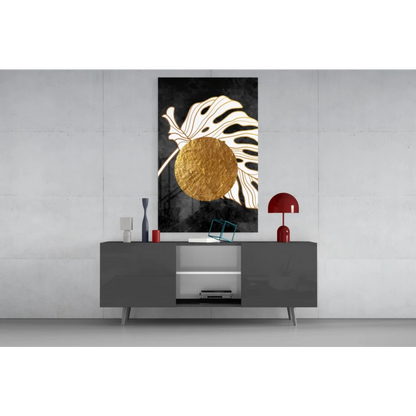 Black and gold glass wall art with textured circle on monstera leaf