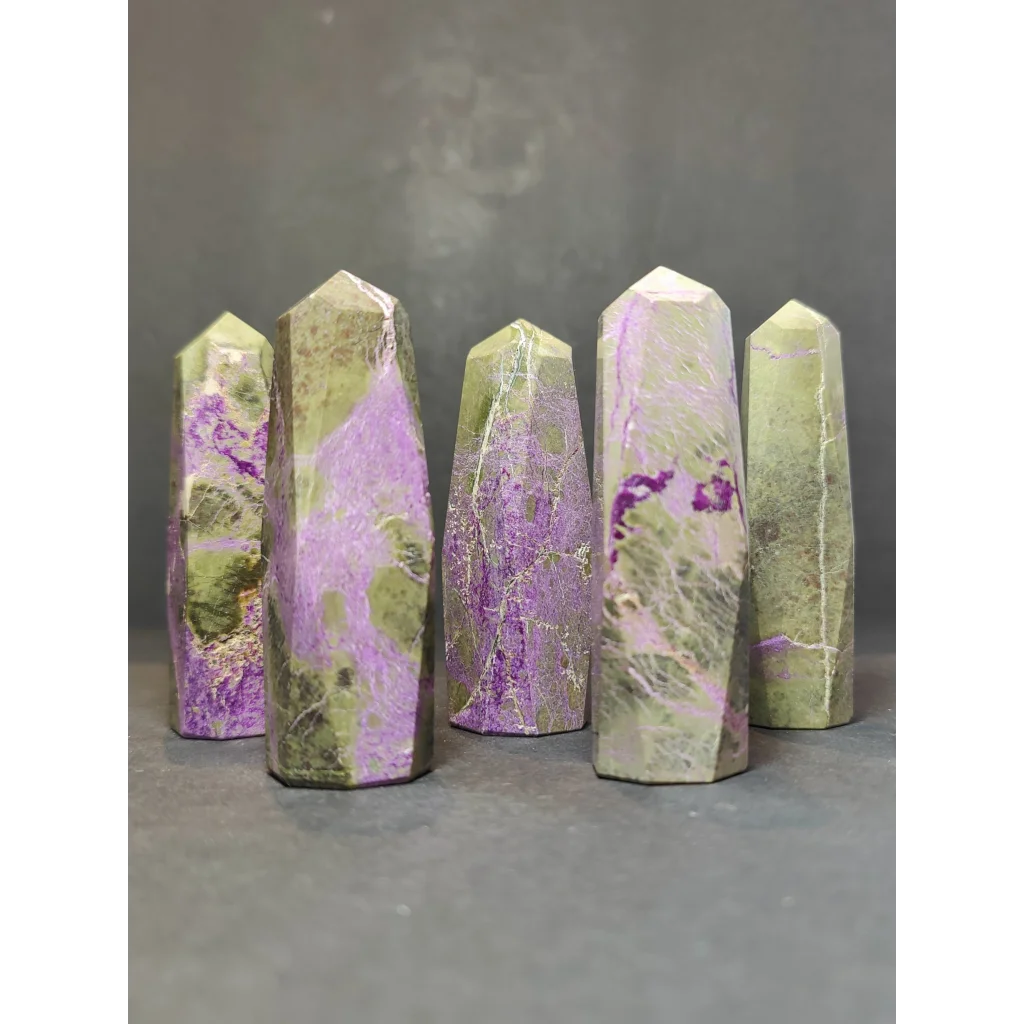 Five polished green and purple atlantisite tower sculptures with faceted geometric design in a polished tower sculpture set