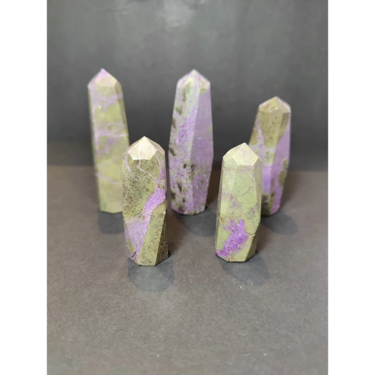 Five polished purple and green polished tower sculptures of atlantisite with faceted geometric cuts displayed upright