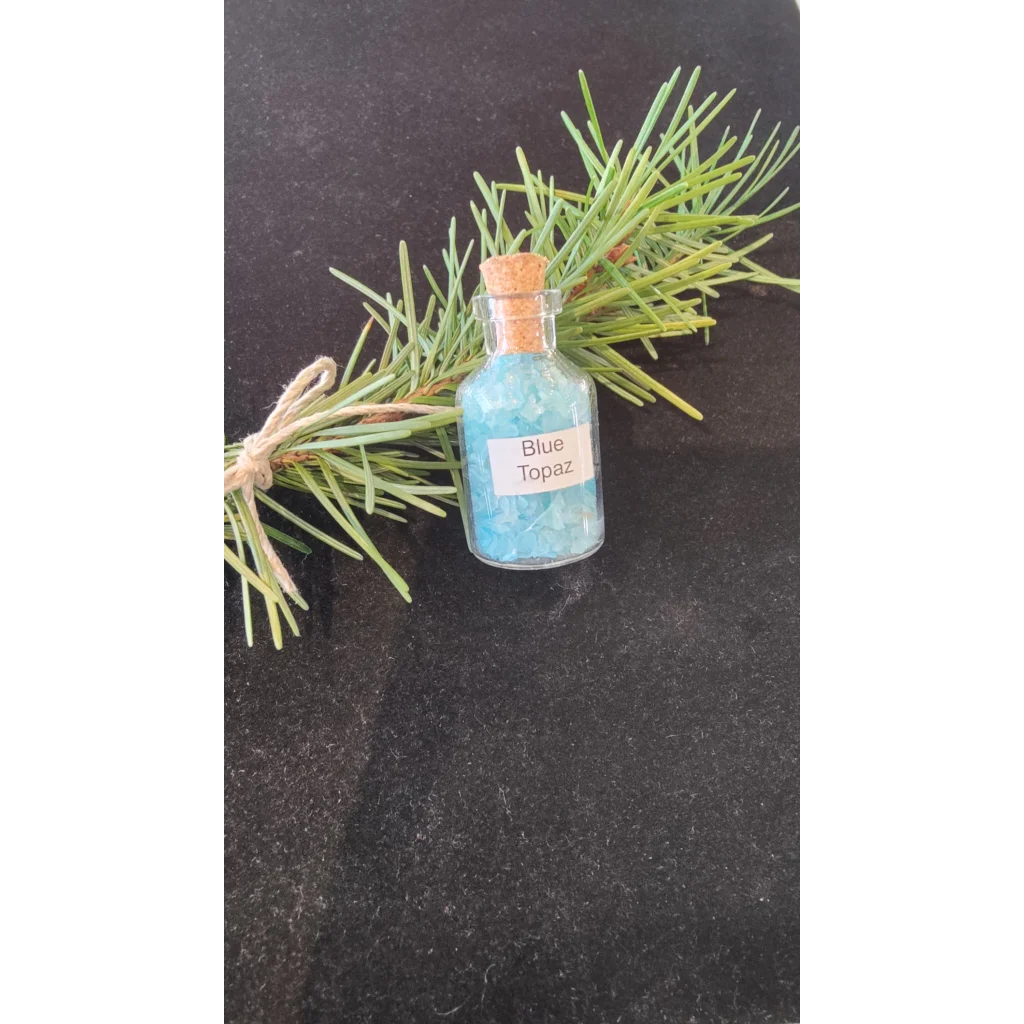 Vibrant blue topaz gemstone bottle with cork and pine branches