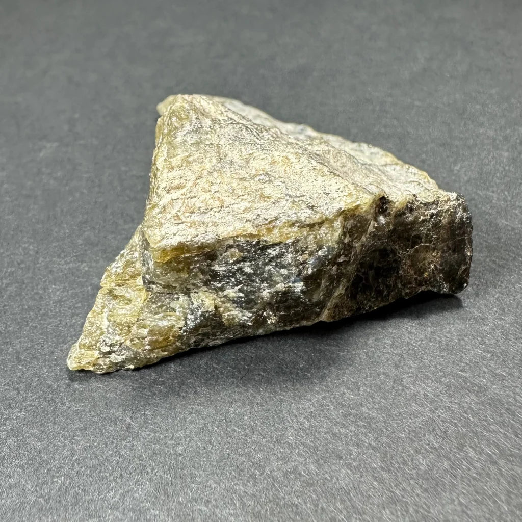 Rough triangular Madagascar labradorite crystal with mottled greenish-yellow and dark gray surface