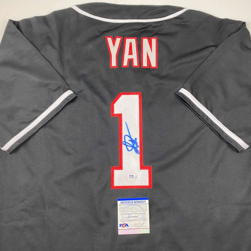 Autographed black YAN baseball jersey with red and white details and blue signature