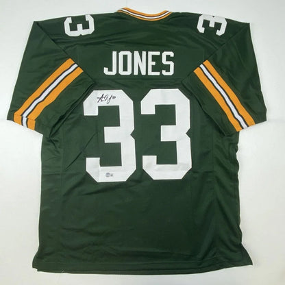 Back of autographed aaron jones green bay green and gold custom football jersey with white lettering number 33 professional sports league