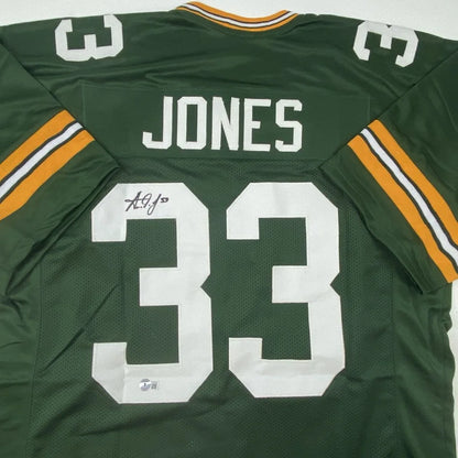 Back side of autographed Aaron Jones Green Bay custom football jersey in green and gold with white professional sports league lettering