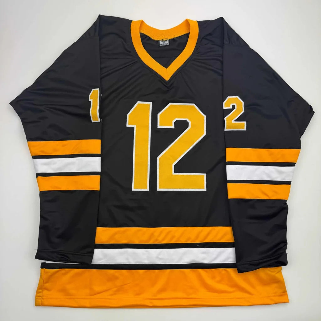 Black hockey jersey with gold and white stripes and number 12 from professional sports league
