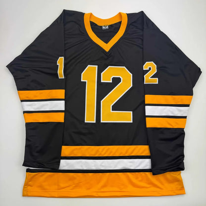 Black hockey jersey with gold and white stripes and number 12 from professional sports league