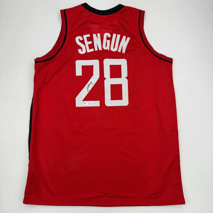 Back side of a red autographed alperen sengun professional sports jersey with black trim and white lettering number 28