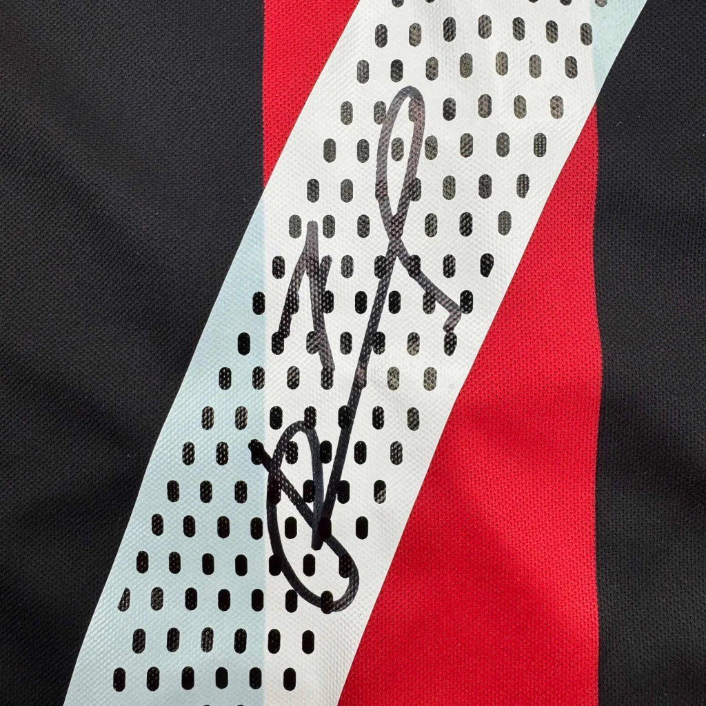 Black ink signature on white perforated stripe of ac milan red and black soccer jersey autographed by andriy shevchenko