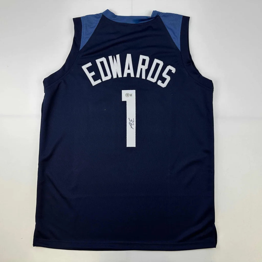 Navy blue sleeveless custom basketball jersey with white lettering number one and autographed back from professional sports league player Anthony Edwards