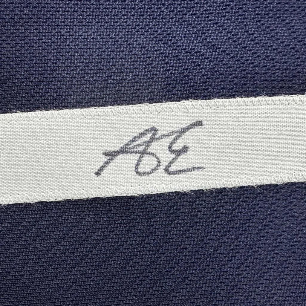 Navy blue textured fabric custom jersey with white woven label bearing handwritten ae initials from professional sports league