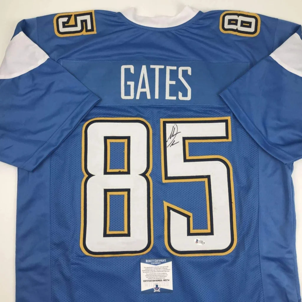 Back side of an autographed blue and white custom jersey with gold trim featuring gates 85 from professional sports league