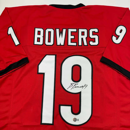 Back side of a red custom jersey signed by Brock Bowers featuring white and black lettering from a professional sports league