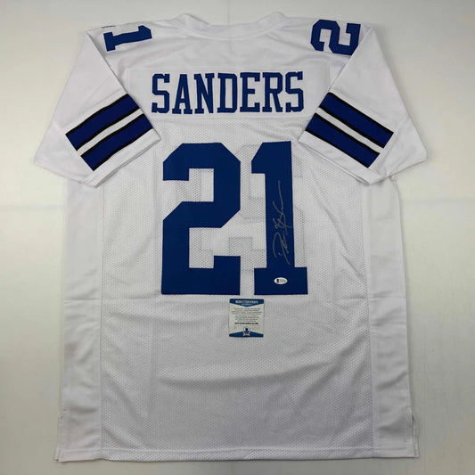 Back side of an autographed white dallas cowboys custom jersey with blue lettering and number 21 featuring sanders