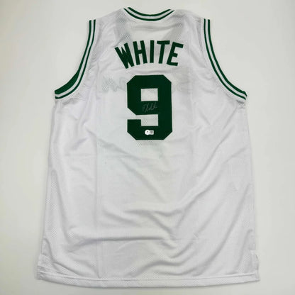 Back side of a white mesh basketball custom jersey with green trim featuring derrick white autograph and bold number 9