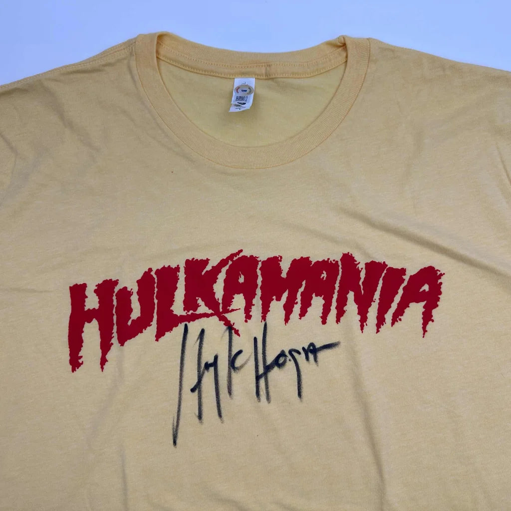 Autographed Hulk Hogan Hulkamania beige cotton T-shirt with red lettering and black signature, Beckett BAS COA