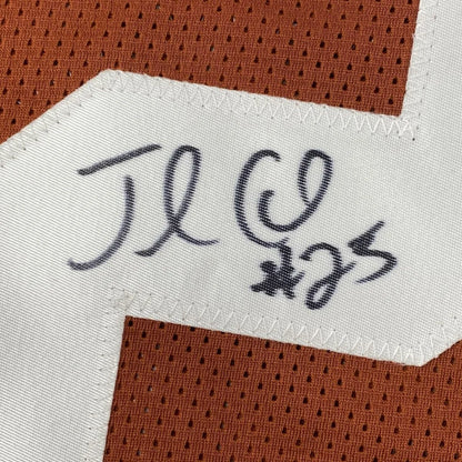 Close-up of an autographed jamaal charles texas orange custom jersey with white fabric tag and black signature on brown mesh