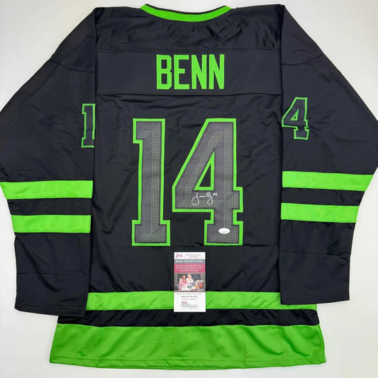 Back of a black Jamie Benn Dallas hockey jersey with neon green trim number 14 and autographed signature professional sports league