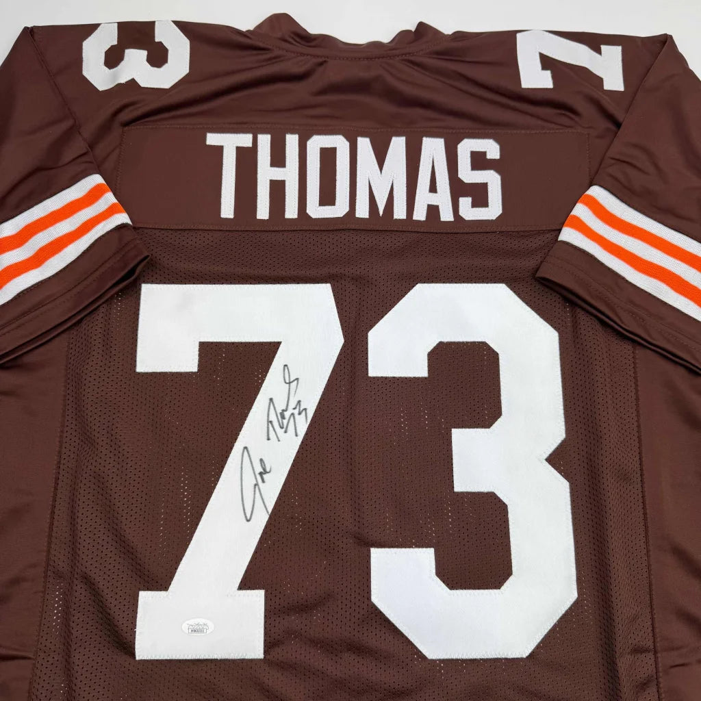 Autographed brown football jersey with white lettering and orange stripes signed by joe thomas from professional sports league