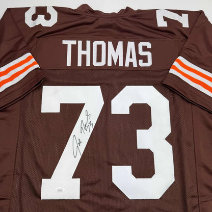 Autographed brown football jersey with white lettering and orange stripes signed by joe thomas from professional sports league