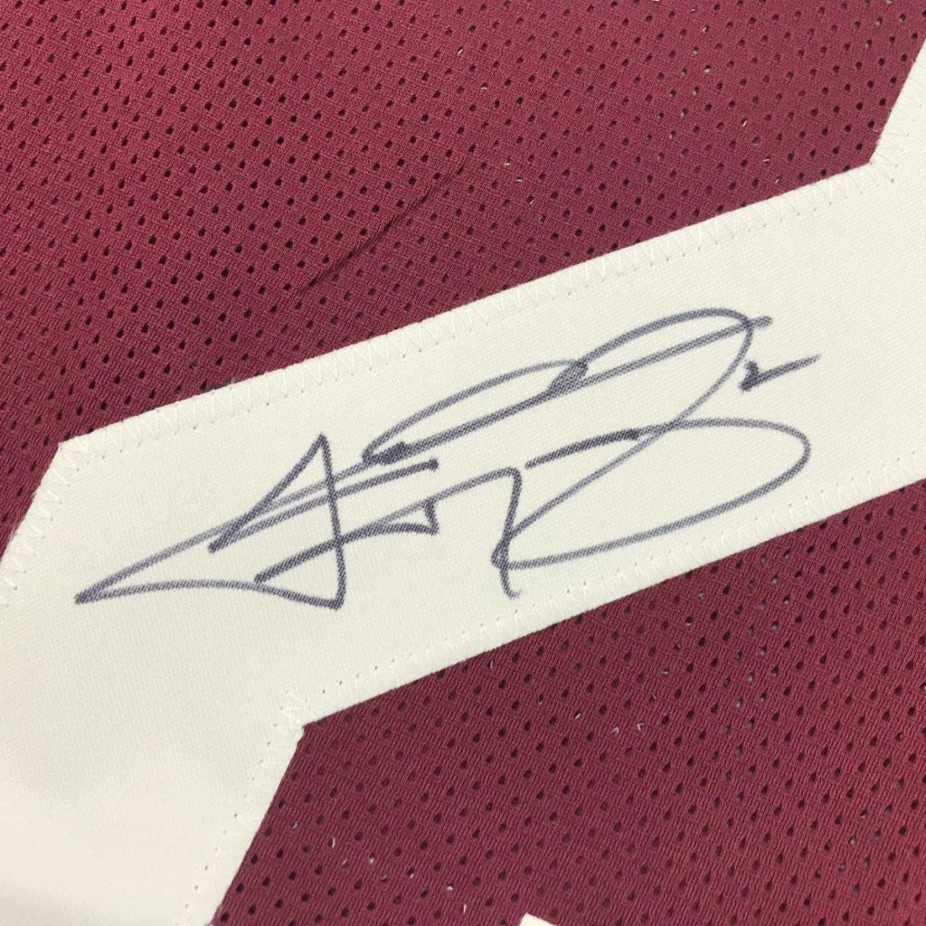 Gray ink signature on white fabric patch stitched on maroon perforated custom jersey from professional sports league