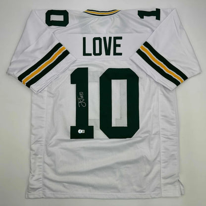 Back side of autographed white green bay packers custom jersey with black gold trim and bold green love 10 lettering
