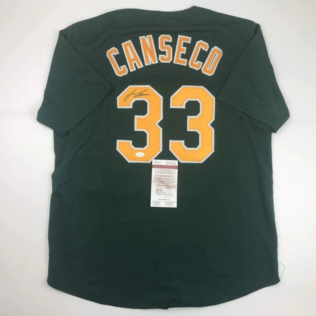 Dark green baseball jersey with ’CANSECO’ and ’33’’ in yellow and white, autographed above the numbers, and authenticated by PSA.